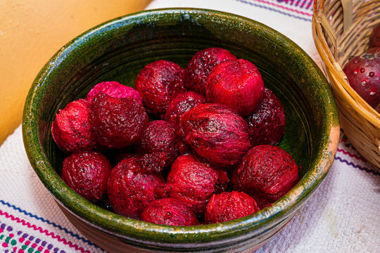 Peeled red prickly pears inside a green clay pot 