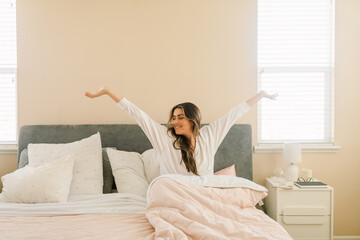 Latin woman in bed waking up positively