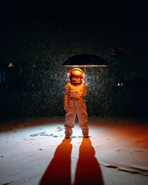 Astronaut standing under rain at night