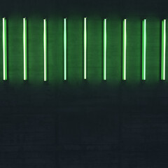 Some bright, green neon lights on a rough concrete wall. Horizontal alligned.