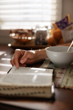 Man reading the bible at kitchen table.