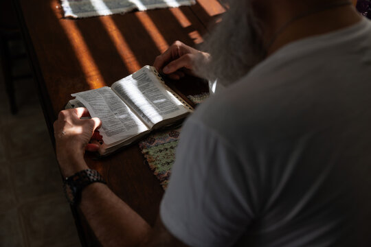 Man reading the bible at kitchen table.