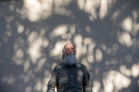 Man lenaing on wall enjoying sunshine.