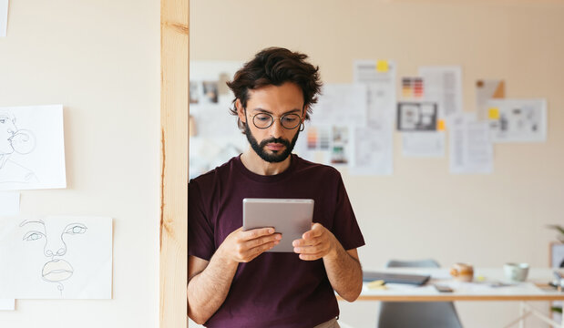 Hispanic designer reading data on tablet