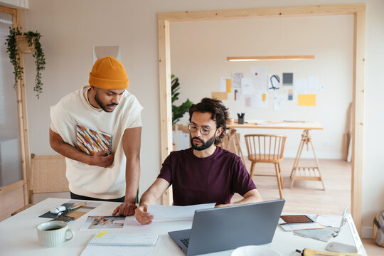 Male designers discussing papers together