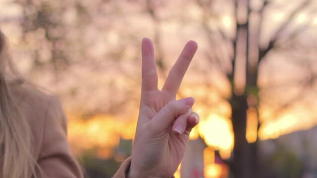 Woman's hands raising two fingers up, sign of peace victory, letter V, outdoor
