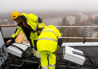 A mobile network technician is preparing 5G equipment on a rooftop 