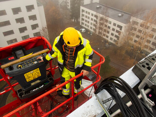 5G network installation, technicians work on a building using the lift