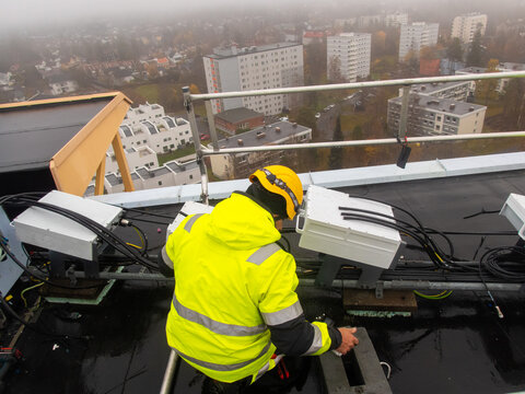 A mobile network technician is preparing 5G equipment on a rooftop 