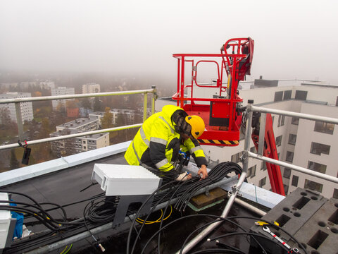 A mobile network technician is preparing 5G equipment on a rooftop 