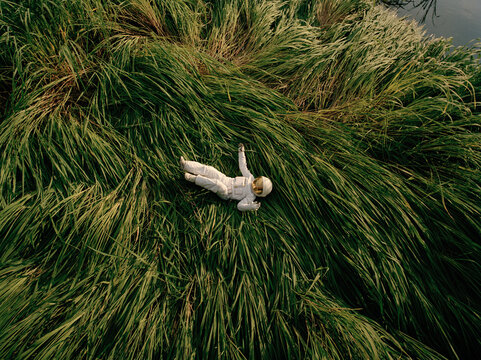 Astronaut lying on grass in nature
