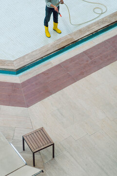 Unrecognizable worker cleaning a dirty swimming pool