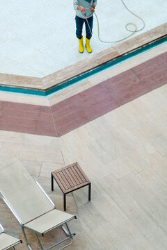 Unrecognizable worker cleaning a dirty swimming pool