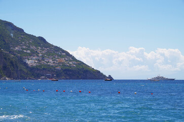 Luxury motor yachts anchoring at sea ashore of Positano, Amalfi Coast for deluxe summer Med vacation
