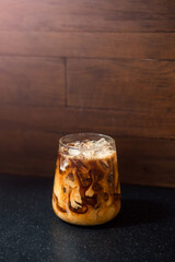 Ice coffee on a table with cream being poured into it showing the texture 