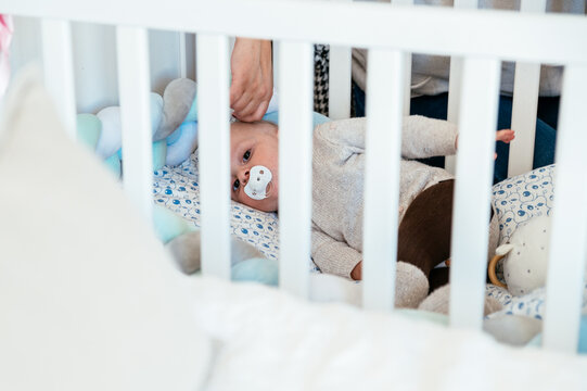 Crop mother putting baby for sleeping in cot