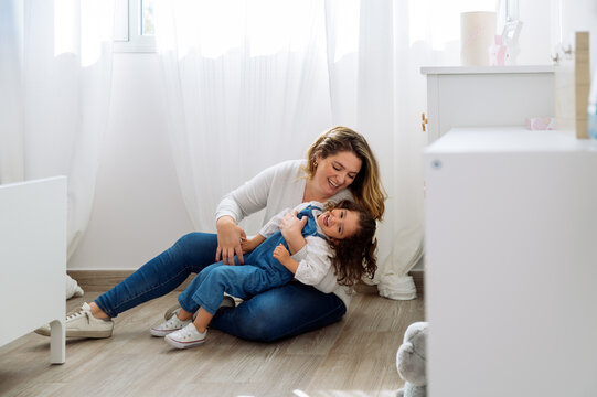 Happy mother having fun with daughter in kid bedroom