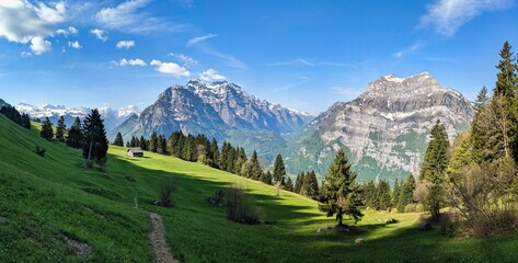 Fantastic morning mood in the mountains of glarus. Sun on the alp. View of an alpine hut in front of the big mountian