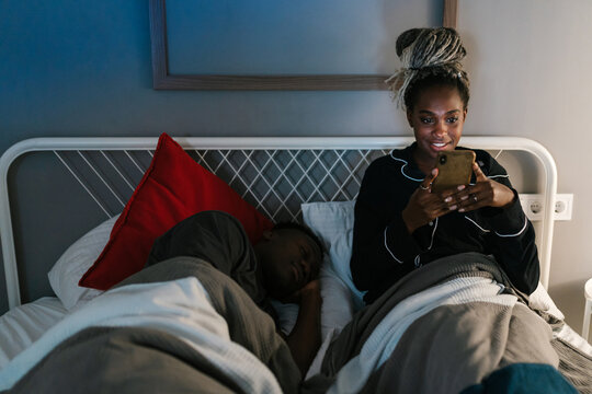 Smiling woman browsing smartphone at night