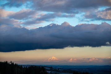 A view towards the horizon in winter in Oregon, soft golden light on Mt Hood under bands of clouds.