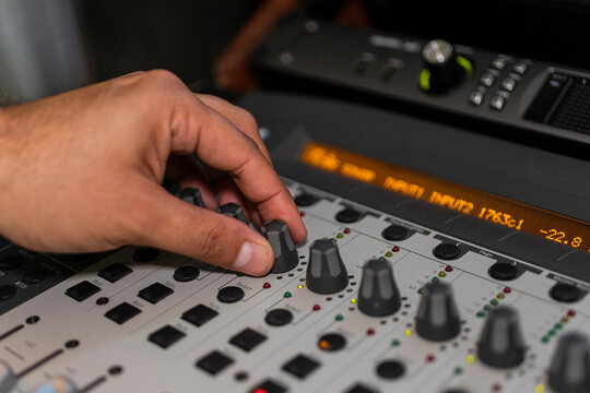 Closeup of a hand moving dial buttons from an audio console 