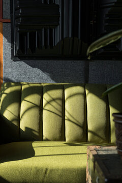 A morning light on a green couch in a dark room