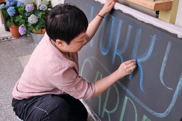 Closeup Asian woman creating chalk drawing on blackboard