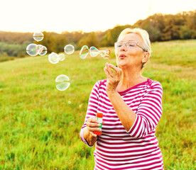 woman outdoor senior elderly happy fun retirement vitality bubble soap blowing active old nature...