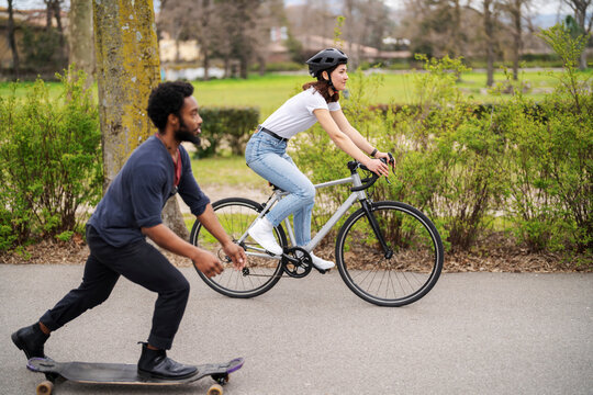 Multiracial friends racing on bike and longboard