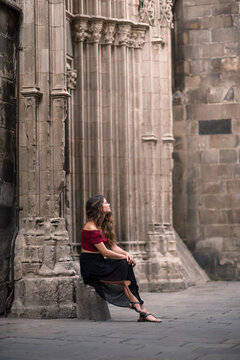Portrait of a chic woman sitting on old cathedral entrance