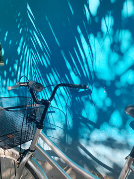 summer, bicycle near blue wall with shadow of palm tree