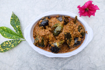 Top view of Indian style brinjal or eggplannt gravy spicy curry. Served decorated bowl on white...