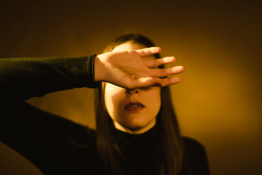 Woman covering her face with one hand with a feeling of fear in studio