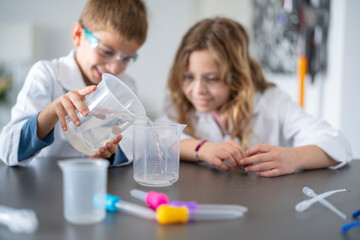 Girl and boy pouring chemicals into jug