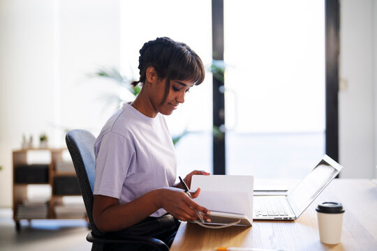 Black freelancer checking notes in planner