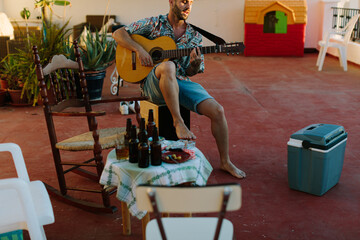 Man playing the guitar in a terrace with chairs and tables