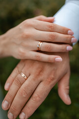 Hands with wedding rings, close-up, isolated. Happy bride and groom after the wedding ceremony. Walk in the green botanical garden.