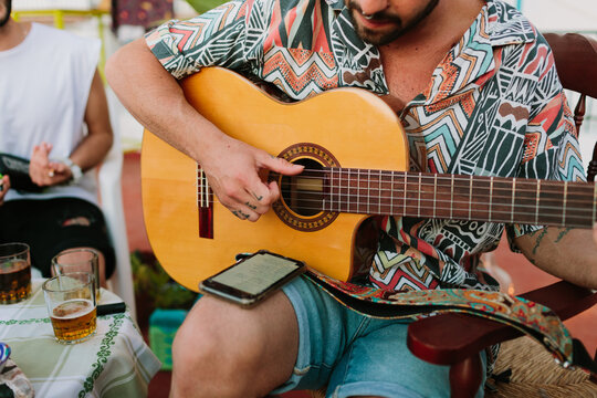 Man looking the lyrics on the phone and playing the guitar