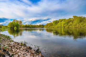 Photo of a  summer landscape with a cloudy skies.  Beautiful spring green landscape with  flowing river and  fluffy clouds. Beautiful nature on spring. No people.