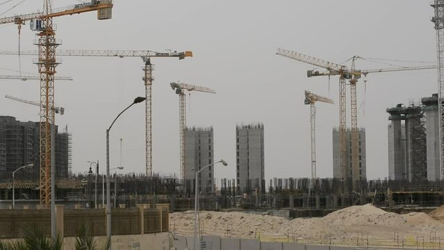 Construction site of new buildings in Egypt, acres of luxurious real estate residential buildings under construction with cranes, selective focus