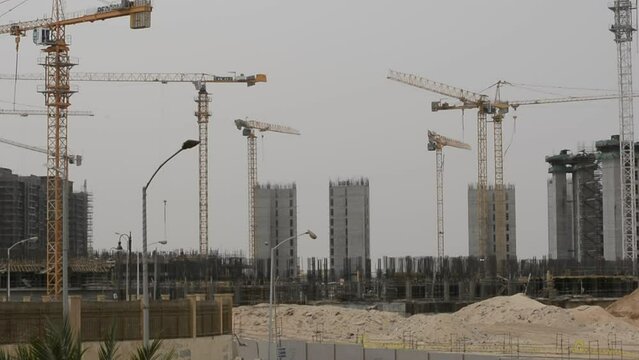 Construction site of new buildings in Egypt, acres of luxurious real estate residential buildings under construction with cranes, selective focus