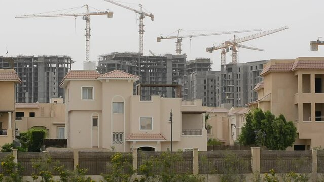 Construction site of new buildings in Egypt, acres of luxurious real estate residential buildings under construction with cranes, selective focus