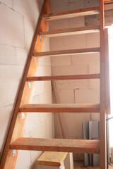 Wooden staircase to the upper floor against the background of foam concrete walls
