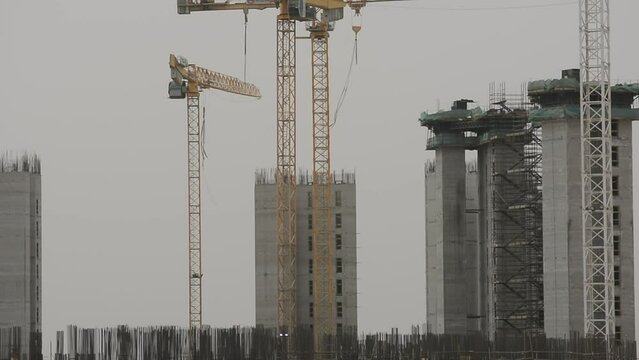 Construction site of new buildings in Egypt, acres of luxurious real estate residential buildings under construction with cranes, selective focus