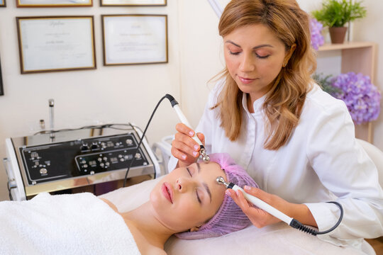 Cosmetologist making a woman a therapeutic procedure on a face.  Beautician makes medical procedures using a professional  equipment. Woman in a spa salon on cosmetic procedures for facial care.