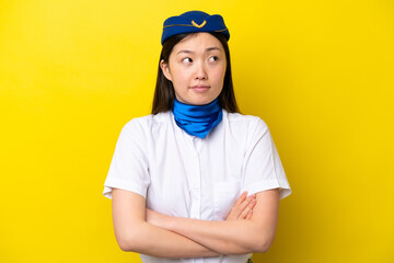 Airplane Chinese woman stewardess isolated on yellow background making doubts gesture while lifting the shoulders