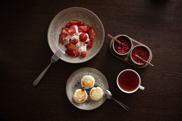 Tasty and healthy breakfast overhead view. Tea with jam, cheese pancakes, burrata salad with tomatoes