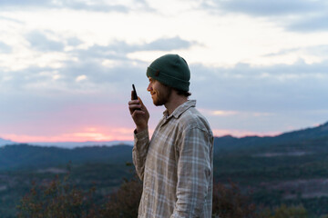 Portrait of happy man in nature at sunset using phone