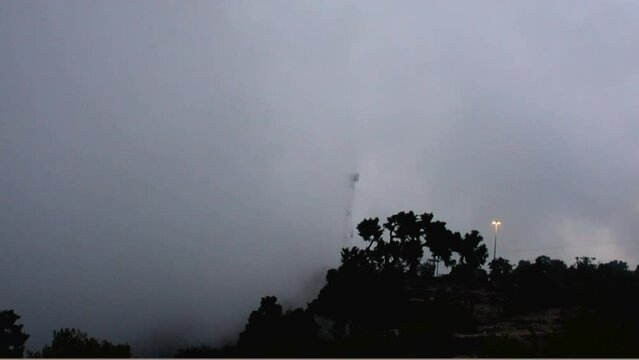 Timelapse of the mist of the clouds along the signal tower and street light