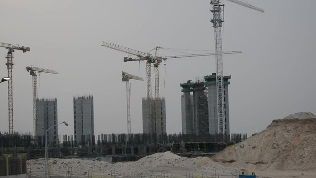 Construction site of new buildings in Egypt, acres of luxurious real estate residential buildings under construction with cranes, selective focus